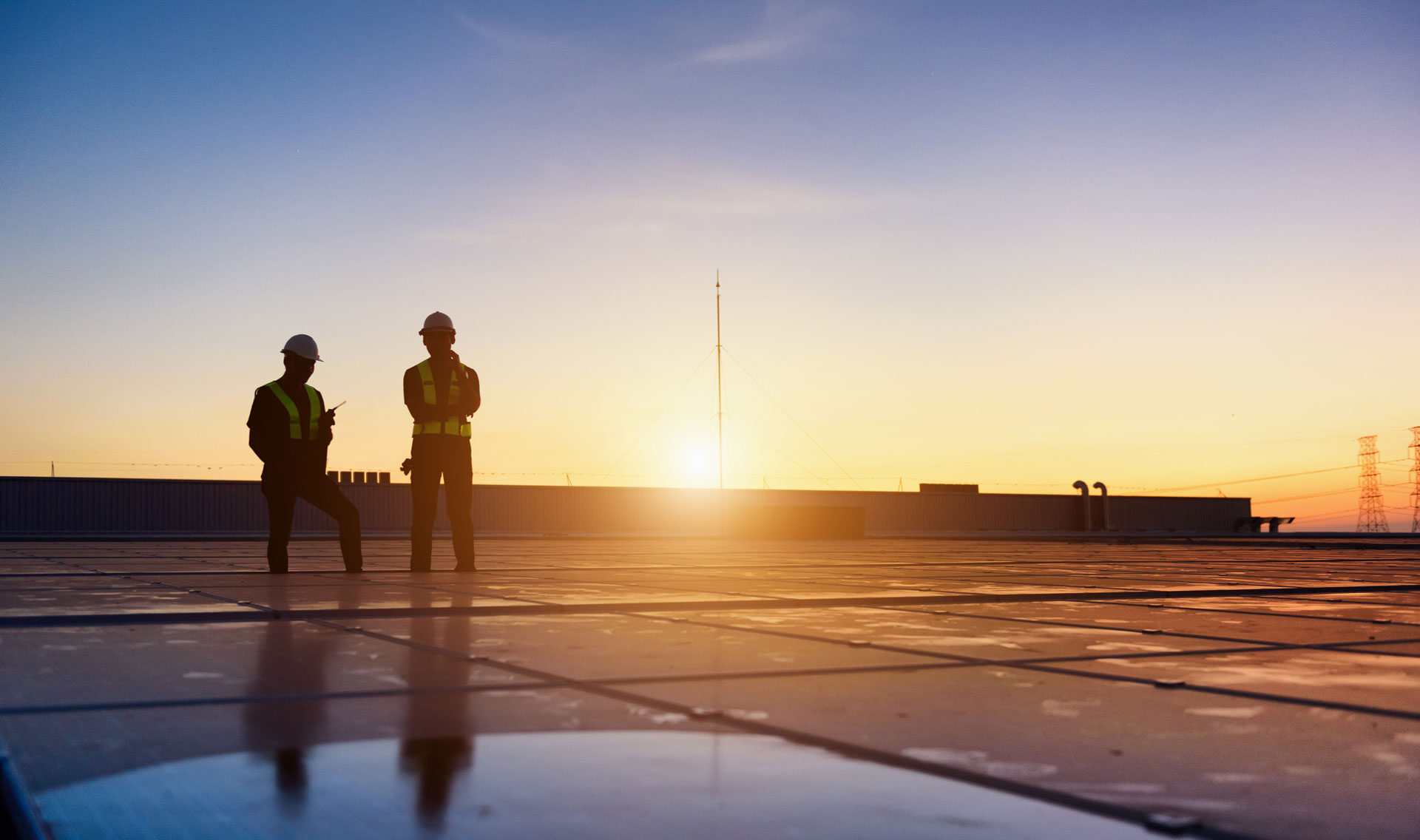 Technikerteam bei der Kontrolle der Photovoltaikmodule auf einem Fabrikdach